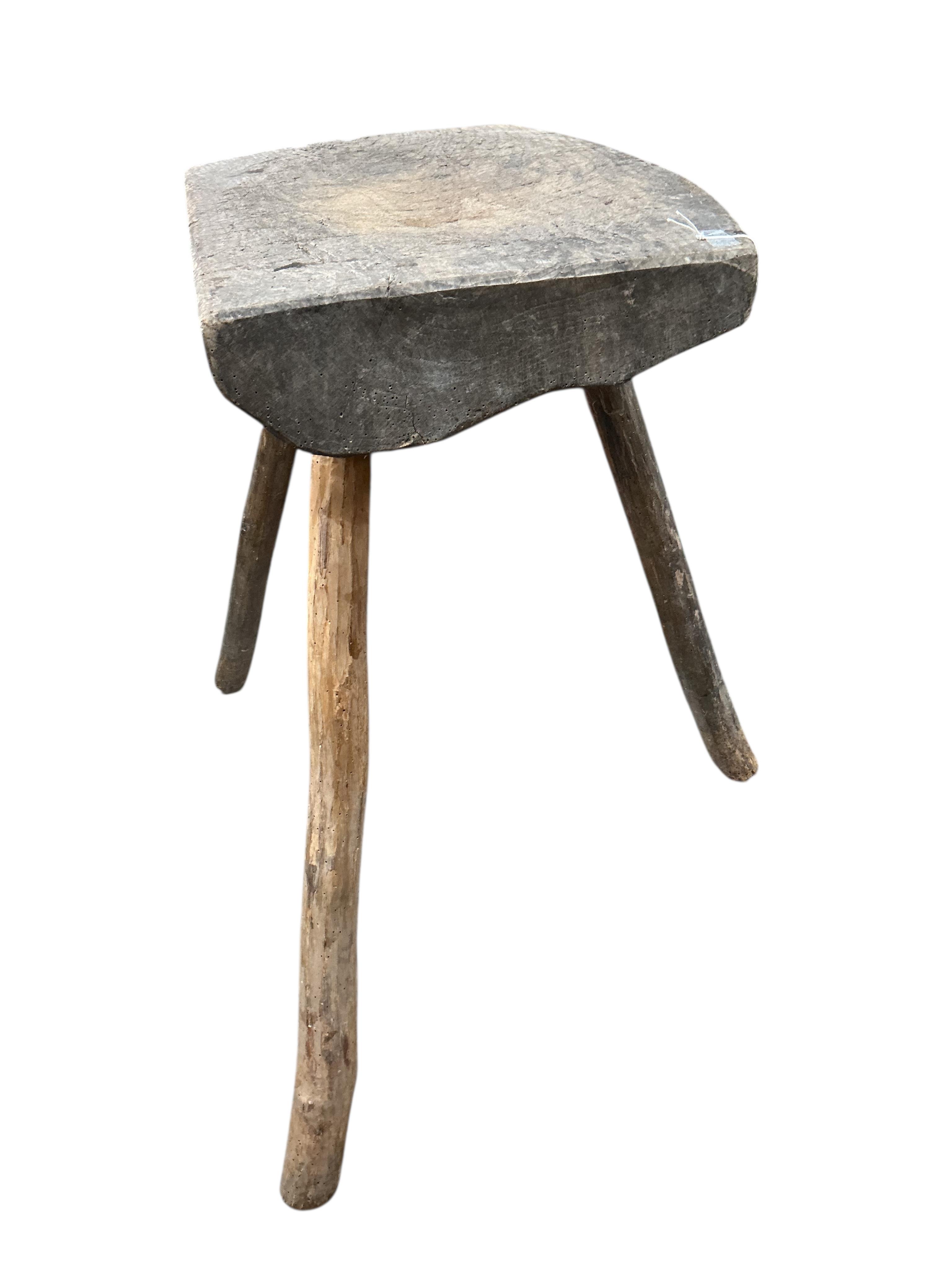 A French Provincial elm three legged block, width 54cm, depth 41cm, height 73cm